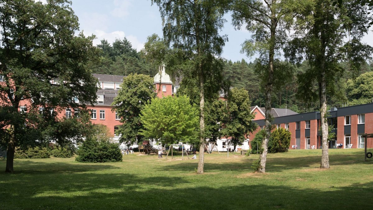 Modernes Klinikgebäude der VAMED Klinik Geesthacht umgeben von Grünflächen – Blick auf den Haupteingang der Rehabilitationsklinik