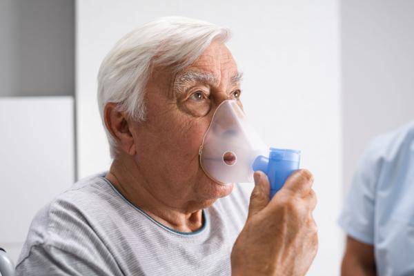 Ein älterer Mann im Krankenhaus atmet mit Unterstützung eines Sauerstoffschlauchs aufgrund von COPD.
