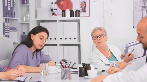 Fachpersonen in Reha-Einrichtung besprechen Unterlagen und Auswertungen zur Qualitätssicherung.