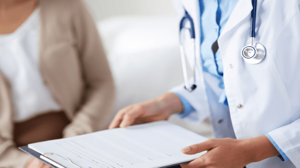 Arzt und Patientin im Aufnahmegespräch mit Checkliste.