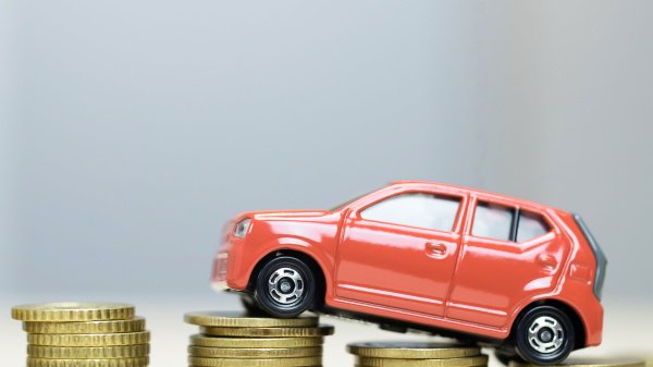 Modellauto auf Münzstapeln als Symbol für Fahrtkosten und Kostenerstattung zur Reha.