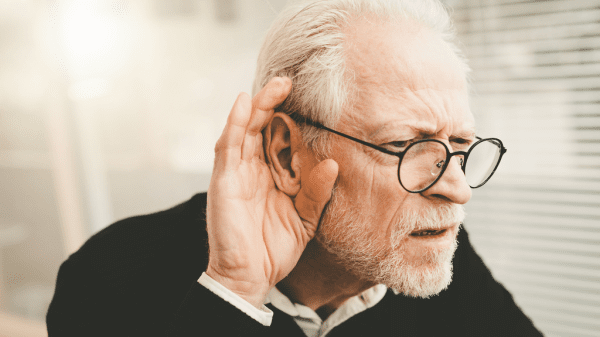 Ein älterer Mann legt die Hand ans Ohr, um besser zu hören, da er unter Hörverlust leidet.