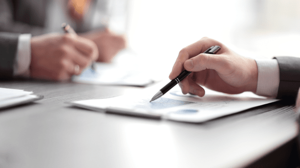 Symbolbild zu Vergütungsverhandlungen: Zwei Personen prüfen Vertragsunterlagen und verhandeln über Konditionen