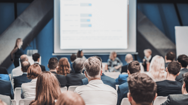 Teilnehmende bei einer Fachkonferenz, Vortragende präsentiert Inhalte vor großem Publikum.