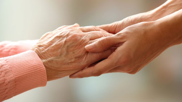 Zwei Hände berühren sich als Symbol für Unterstützung pflegender Angehöriger.