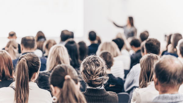 Teilnehmende bei einer Fachkonferenz, Vortragende präsentiert Inhalte vor großem Publikum.