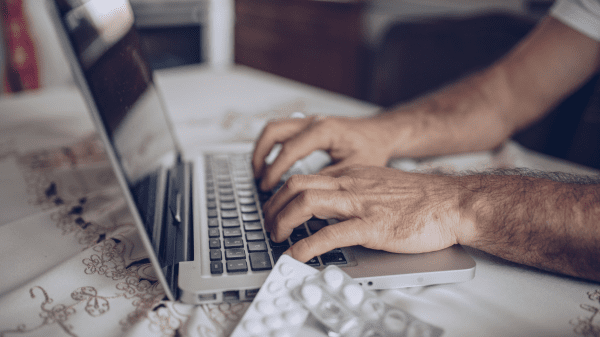 Hände tippen auf Laptop in anonymes Meldeportal im Gesundheitswesen, Medikamentenblister