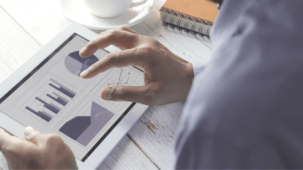 Person betrachtet auf einem Tablet Balken- und Liniendiagramme – Symbolbild für Ergebnisse der PROMs-Studie zur orthopädischen Rehabilitation