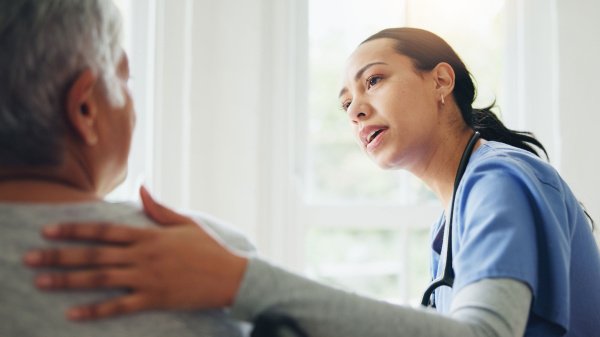 Mitarbeiterin spricht mit einem Patienten. Symbolbild für sprachliche Unterstützung in Rehakliniken.