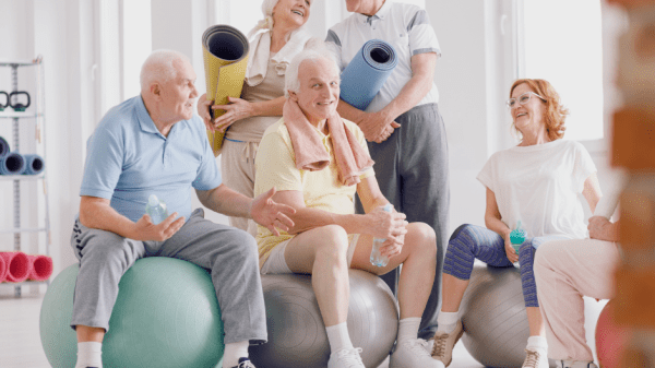 Gemischte Gruppe von Rehabilitanden im Training mit Gymnastikball und Matten