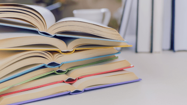 Aufgeklappte Bücher liegen auf einem Stapel übereinander