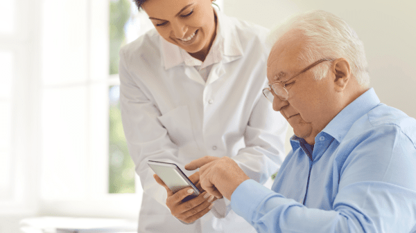 Ärztin unterstützt einen älteren Patienten bei der Nutzung einer Gesundheits-App.
