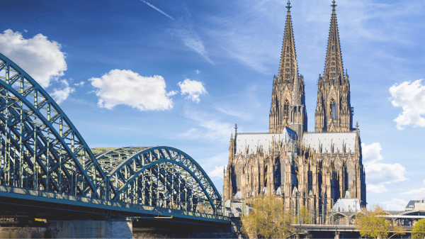 Kölner Dom und Hohenzollernbrücke am Rhein bei sonnigem Himmel in Köln.