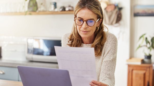 Frau prüft Unterlagen am Laptop und informiert sich über Reha vor einer Rente.
