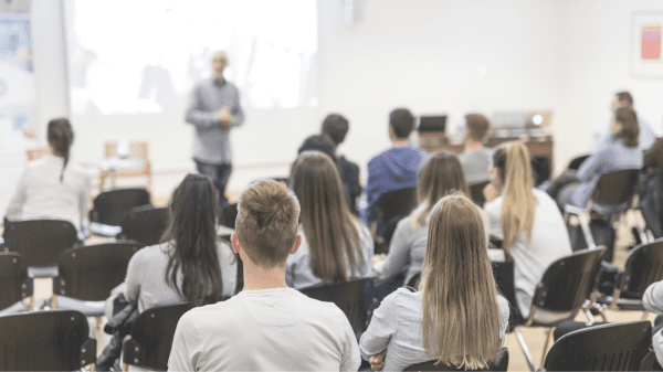 Mehrere Personen sitzen in einem Seminarraum und hören einem Vortragenden zu