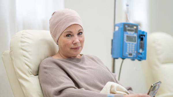 Patientin während einer Chemotherapie in einer Klinik mit Infusionssystem im Hintergrund.