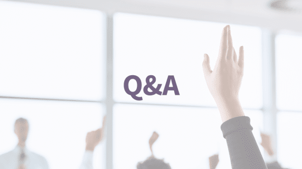 Schriftzug "Q&A" vor hellem Hintergrund mit erhobener Hand einer Person aus dem Publikum