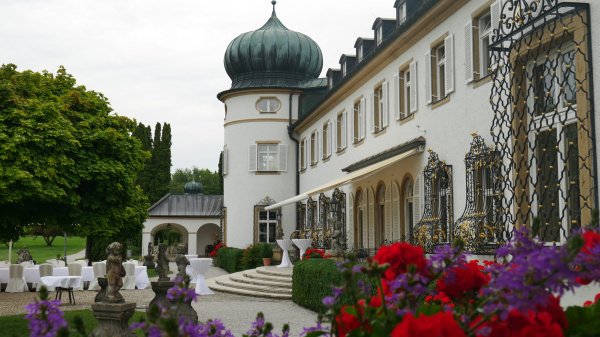 Schloss Höhenried, Außenansicht mit barocker Fassade, verzierten Fenstergittern und gedeckten Tischen im Garten