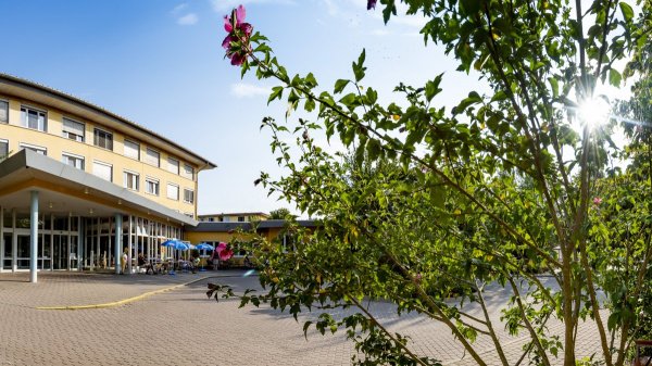 Modernes Klinikgebäude des Reha-Zentrums Plau am See mit Vorfahrt und Begrünung bei Sonne