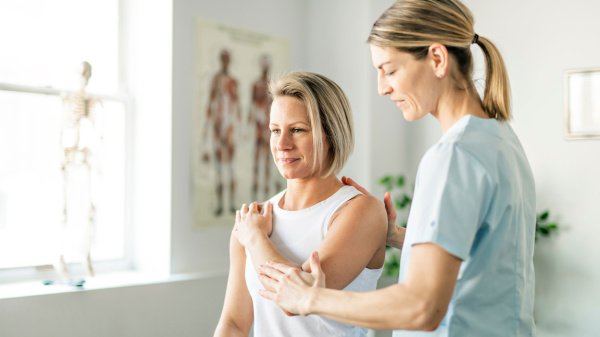 Patientin übt Bewegungsabläufe mit Therapeutin während einer Anschlussrehabilitation.