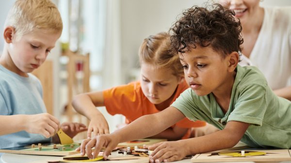 Kinder spielen gemeinsam während einer Reha, begleitet von einer Betreuungsperson.