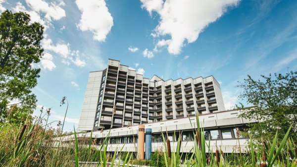 Gebäude der Klinik Roderbirken vor blauem Himmel umrahmt von Bäumen und Sträuchern