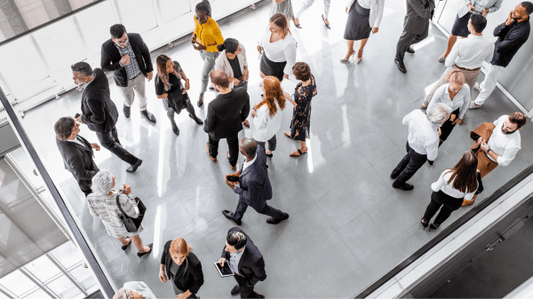 Menschen in Business-Kleidung stehen in Gruppen und unterhalten sich in einer offenen Halle
