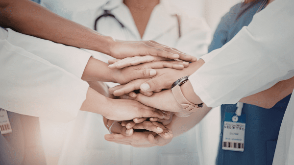 Mitarbeitende legen Hände übereinander als Zeichen für Zusammenarbeit und Patientensicherheit.