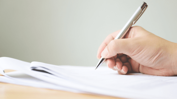 Nahaufnahme einer Hand, die mit einem Stift auf ein Blatt Papier schreibt