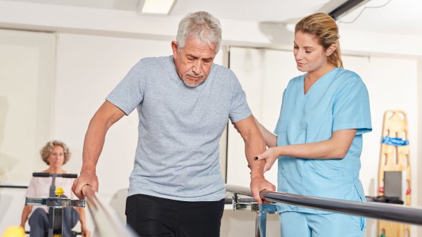 Älterer Mann trainiert unter Anleitung einer Therapeutin in der ambulanten Reha.