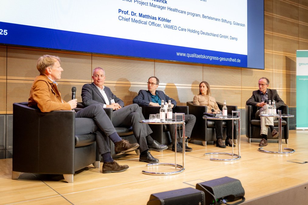 Fünf Expert:innen sitzen auf dem Podium des Neuen Qualitätskongresses Gesundheit 2025 und diskutieren über PROMs und Ergebnisqualität.