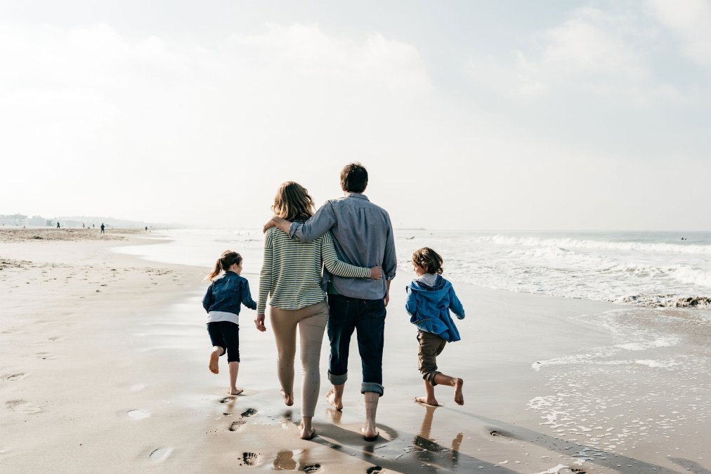 Familie mit zwei Kindern spaziert am Strand während einer Mutter-Vater-Kind-Kur.