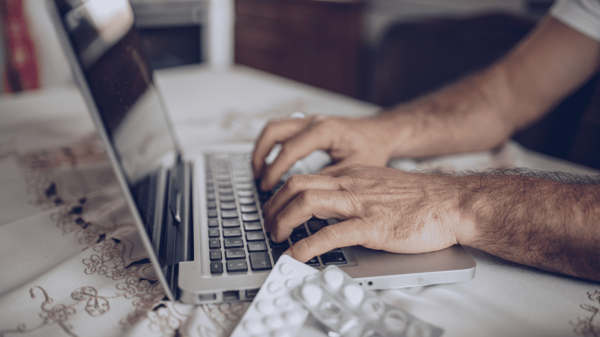 Hände tippen auf Laptop in anonymes Meldeportal im Gesundheitswesen, Medikamentenblister