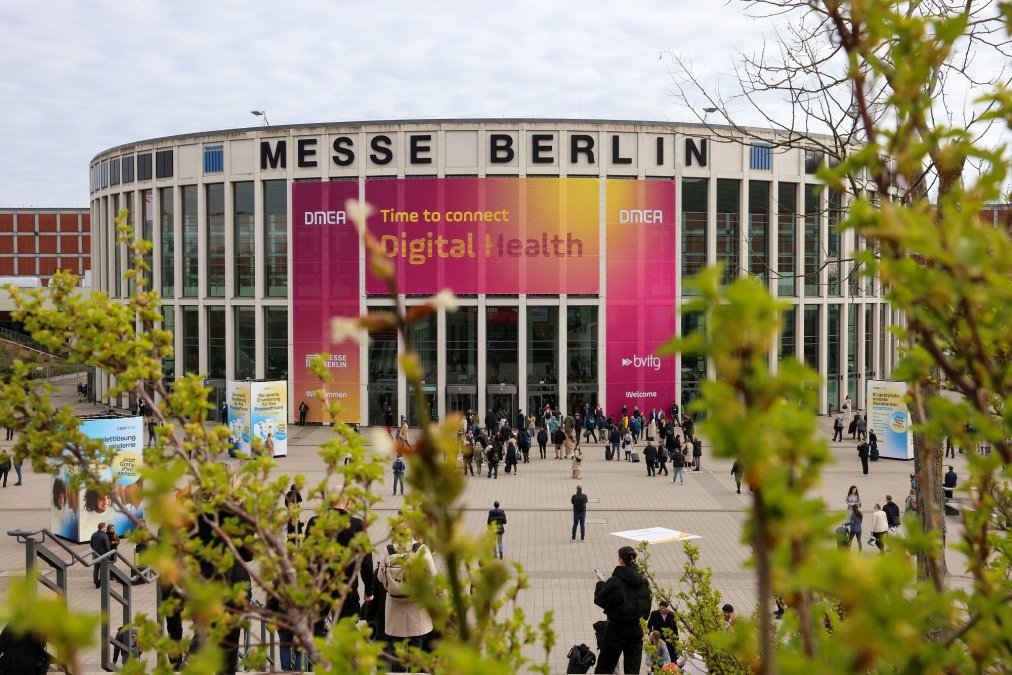 Messe Berlin mit DMEA-Banner „Digital Health“ und Besucher:innen vor dem Eingang.