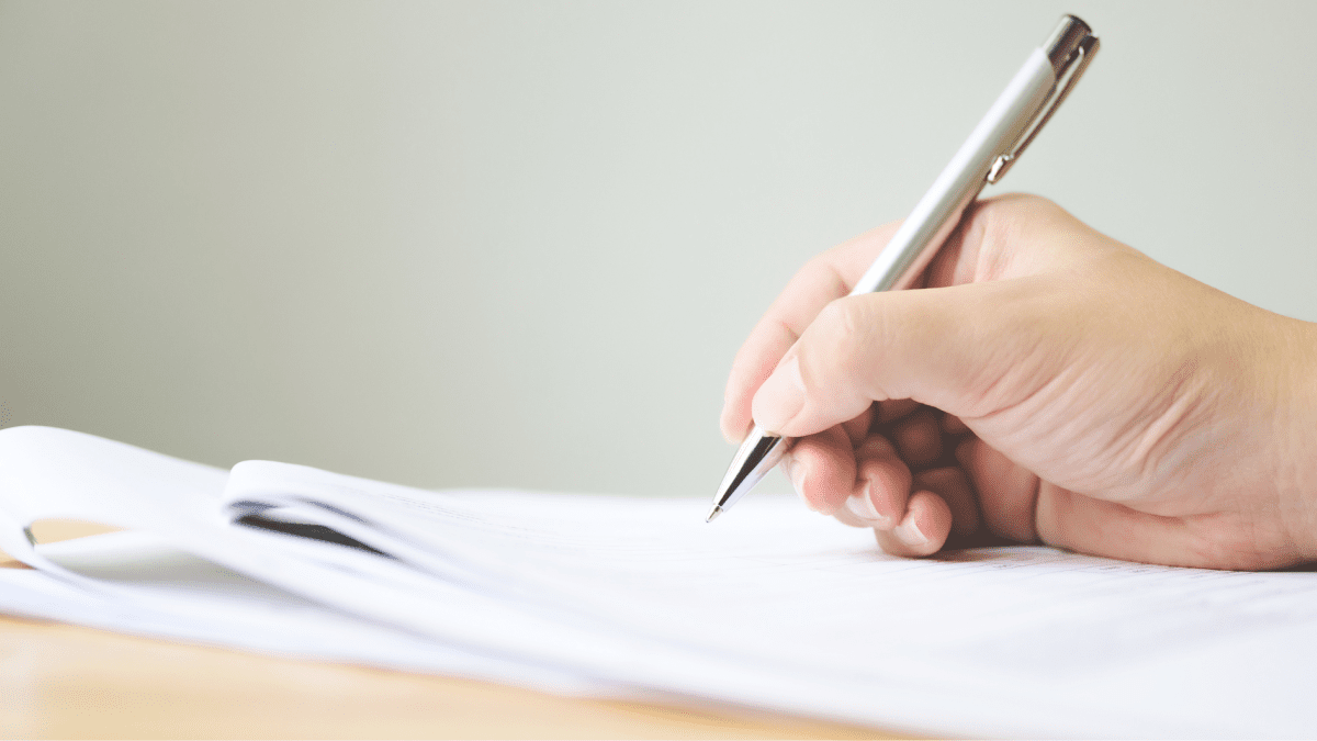 Nahaufnahme einer Hand, die mit einem Stift auf ein Blatt Papier schreibt