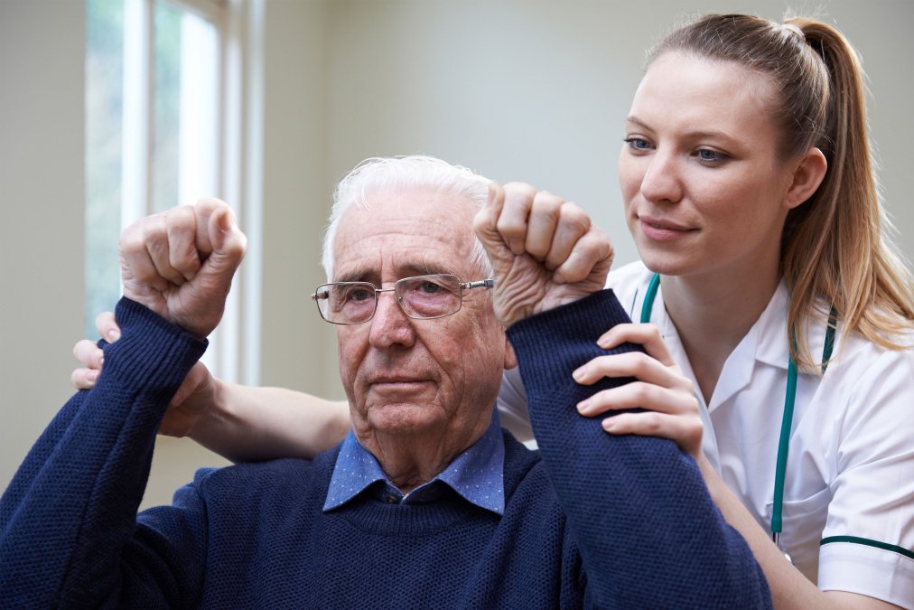 Therapeutin begleitet einen Patienten bei Übungen in der neurologischen Rehabilitation.